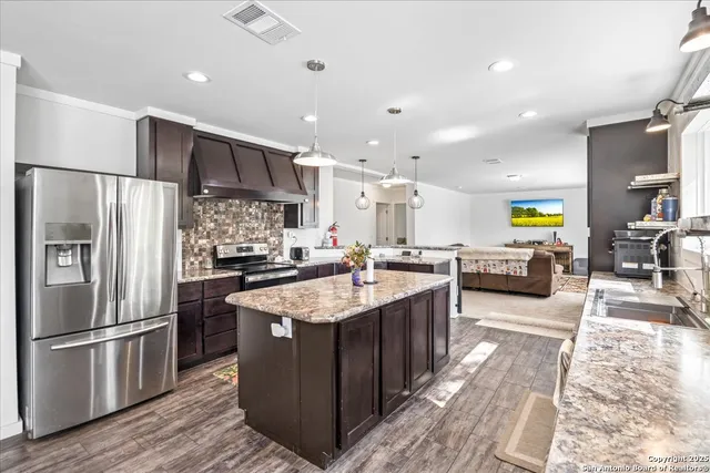 a kitchen with stainless steel appliances granite countertop a sink a stove and a refrigerator