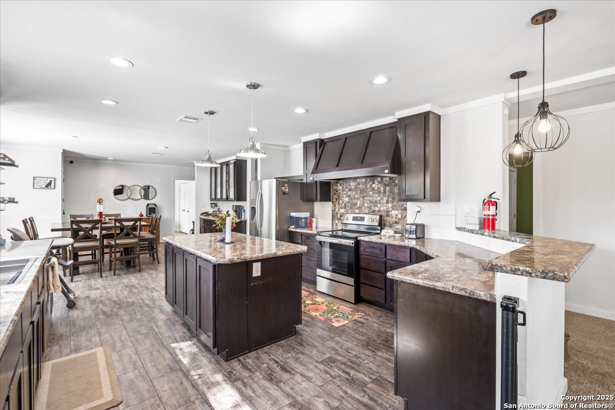 1291 Vivroux Ranch Road Seguin, TX 78155 - Photo 8 of 44 a kitchen with stainless steel appliances kitchen island granite countertop a stove refrigerator and cabinets
