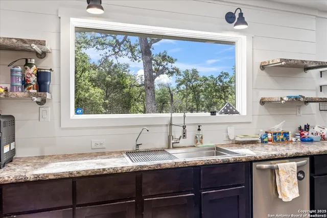 a kitchen with granite countertop a window sink and cabinets