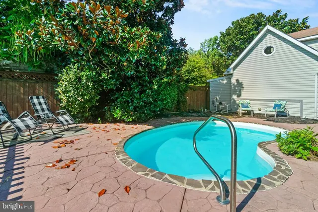 a view of backyard with swimming pool and seating space