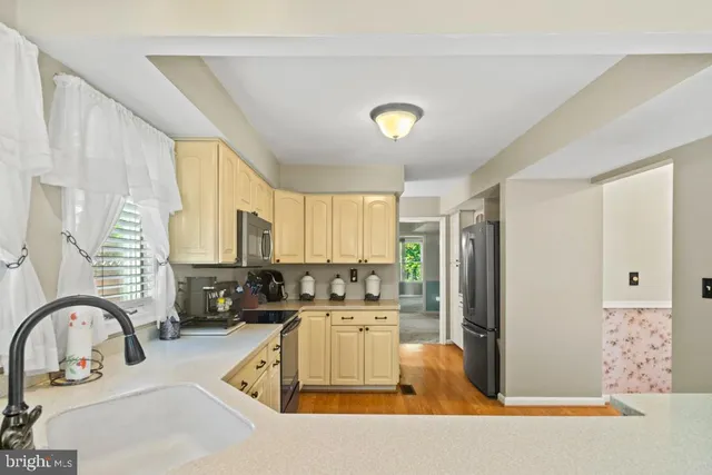 a kitchen with stainless steel appliances a sink a counter top space cabinets a stove and a window