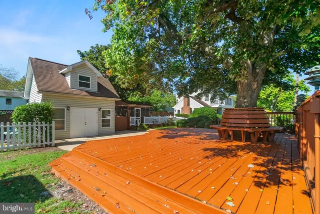 a backyard of a house with wooden fence and large trees
