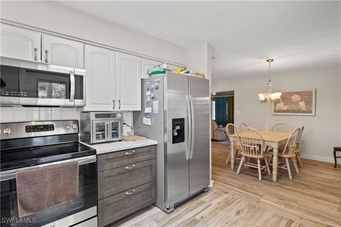 12206 Boat Shell Drive Matlacha Isles, FL 33991 - Photo 19 of 50 a kitchen with stainless steel appliances kitchen island granite countertop a refrigerator a stove a microwave oven a sink with a dining table and chairs