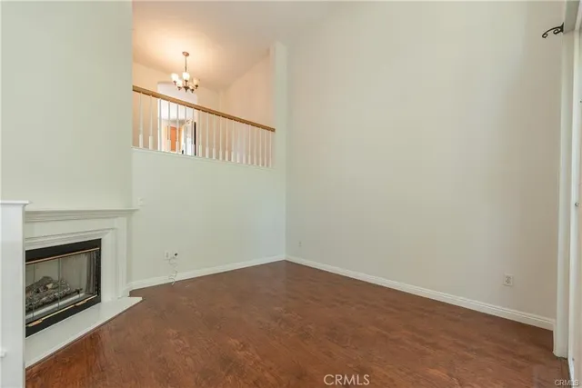 a view of an empty room with chandelier fan and fire place