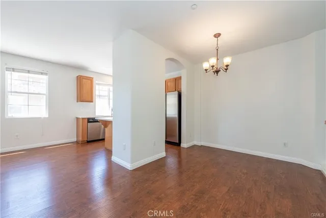 an empty room with wooden floor chandelier and windows