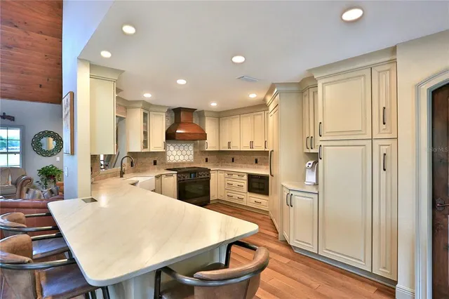 a kitchen with stainless steel appliances a refrigerator a stove a sink dishwasher and white cabinets with wooden floor