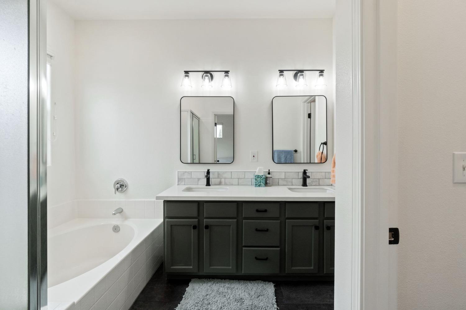 1732 North Avignon Lane Clovis, CA 93619 - Photo 23 of 28 a bathroom with a double vanity sink a large mirror and a bathtub
