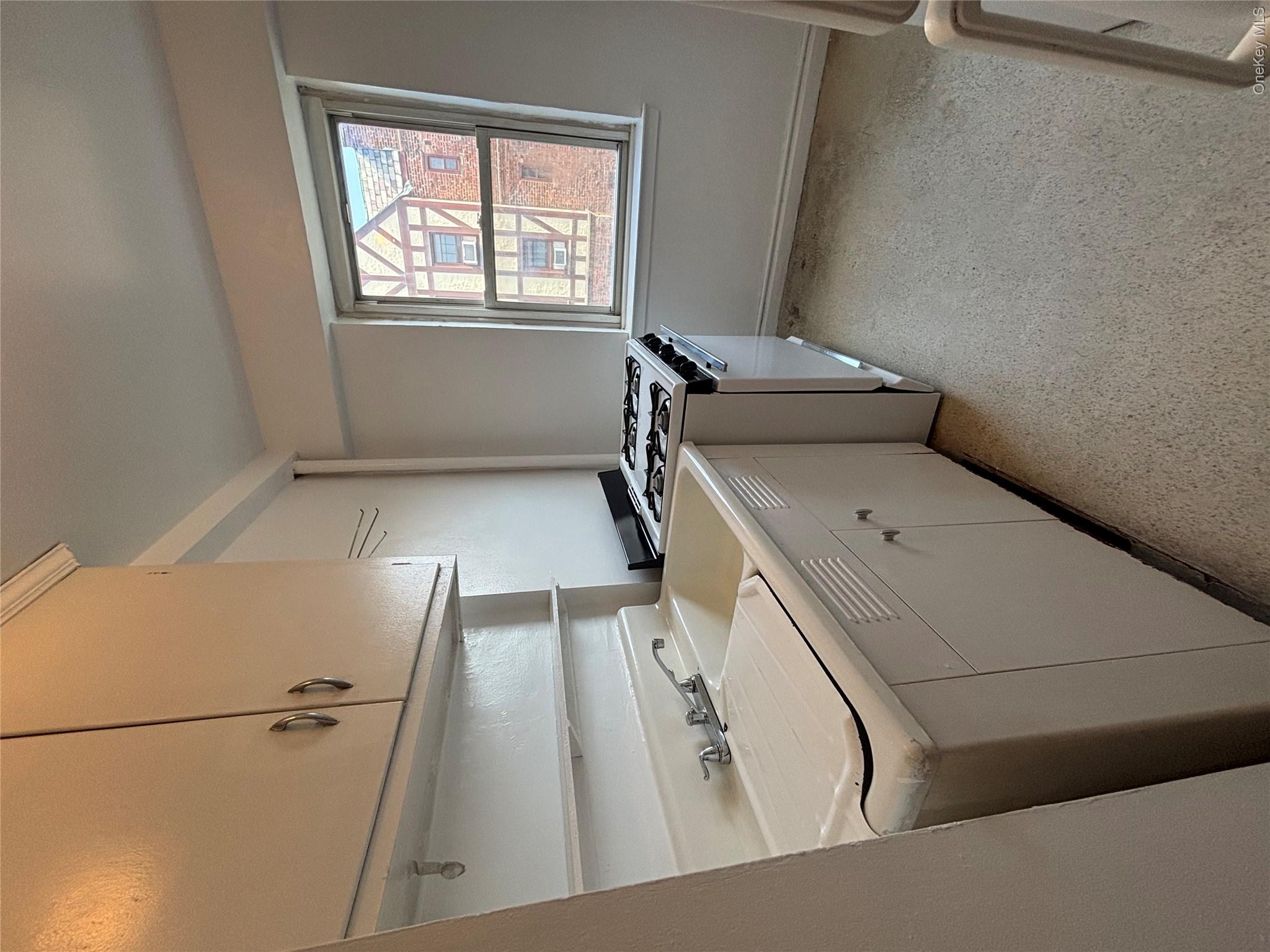 235 Garth Road, Unit A6F Scarsdale, NY 10583 - Photo 4 of 9 Compact kitchen featuring built-in cabinetry, a double basin sink, and a four-burner range