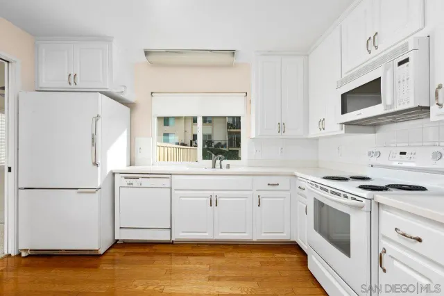a kitchen with white cabinets and white appliances