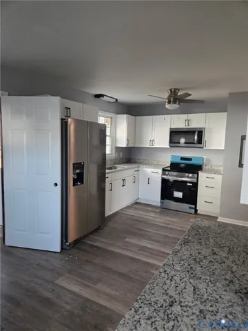 a kitchen with granite countertop a refrigerator and a stove top oven