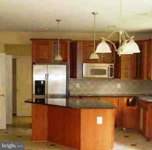 9906 Farm Pond Road Laurel, MD 20708 - Photo 8 of 11 a kitchen with kitchen island a counter top space a sink and refrigerator