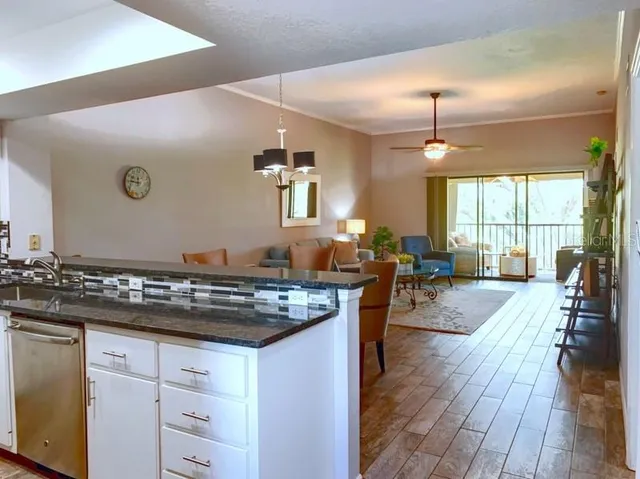 a kitchen with stainless steel appliances granite countertop a stove top oven a dining table and chairs with wooden floor