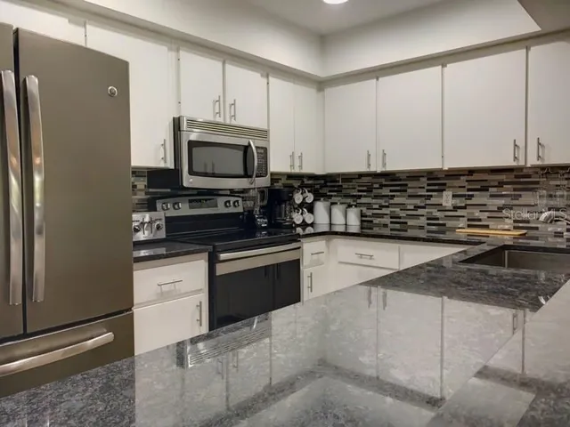 a kitchen with granite countertop a refrigerator stove and microwave