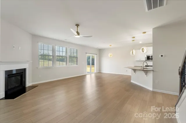 a view of an empty room with a kitchen and fireplace