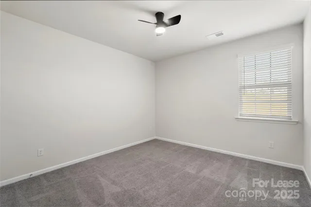 an empty room with a window and ceiling fan