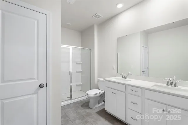 a spacious bathroom with a double vanity sink toilet mirror and shower