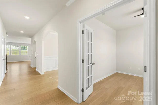 a view of a hallway with wooden floor and a bathroom