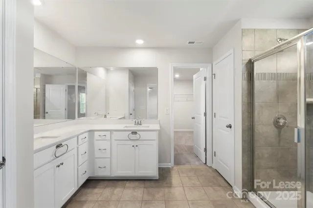 a spacious bathroom with a mirror a shower and a sink