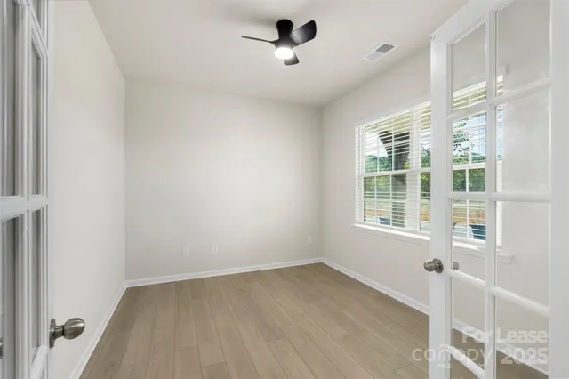 an empty room with wooden floor and windows
