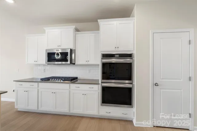 a kitchen with granite countertop white cabinets and stainless steel appliances