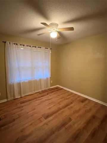 en empty room with wooden floor and fan