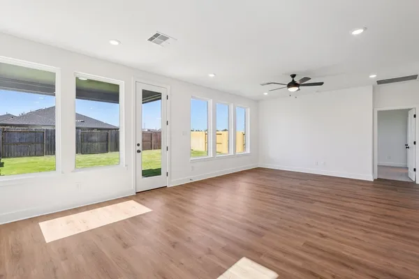 a view of an empty room with a window and wooden floor