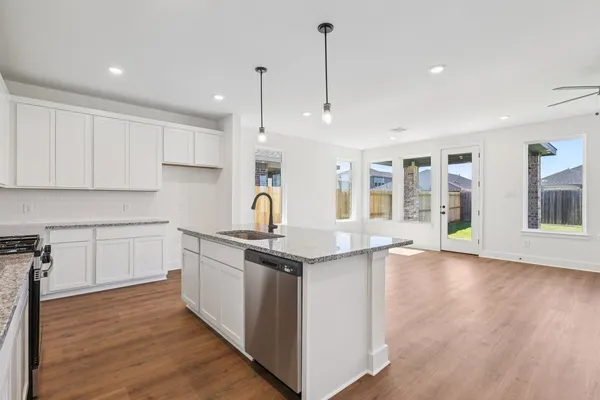 a kitchen with stainless steel appliances granite countertop a sink a stove and a wooden floors