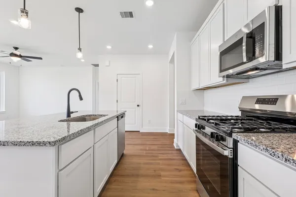 a kitchen with stainless steel appliances granite countertop a white stove top oven and sink