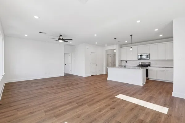 a view of kitchen with kitchen island wooden floors appliances and cabinets