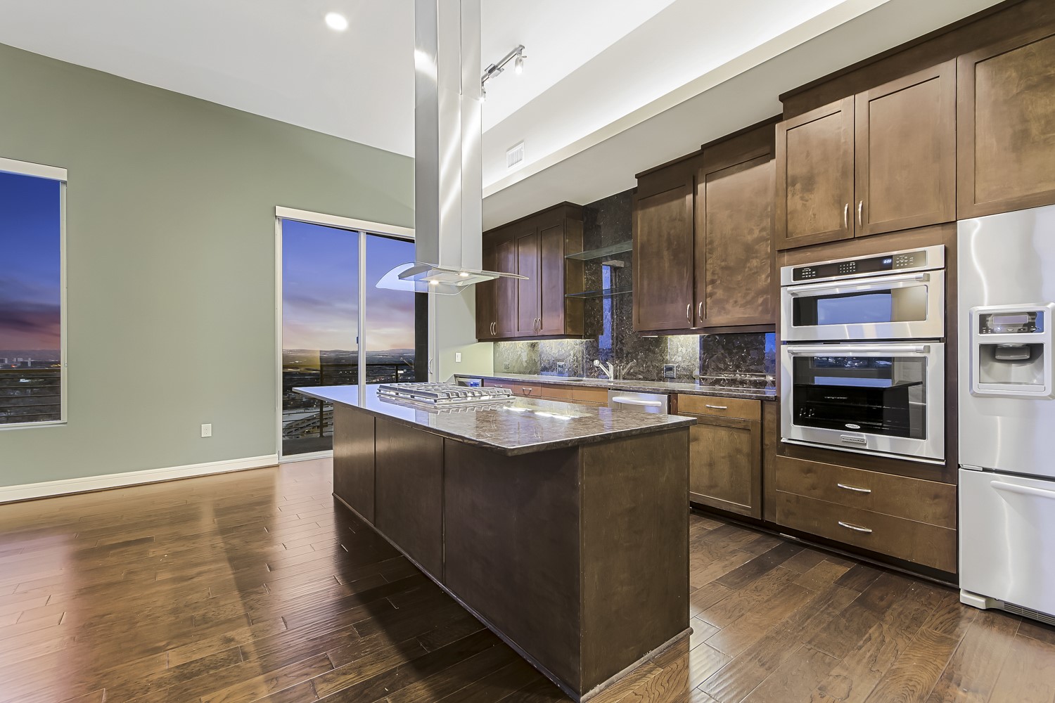 214 Barton Springs Road, Unit 1909 Austin, TX 78704 - Photo 15 of 34 Kitchen featuring dark wood finish cabinetry, stainless steel appliances, tasteful backsplash, island exhaust hood, and dark stone counters
