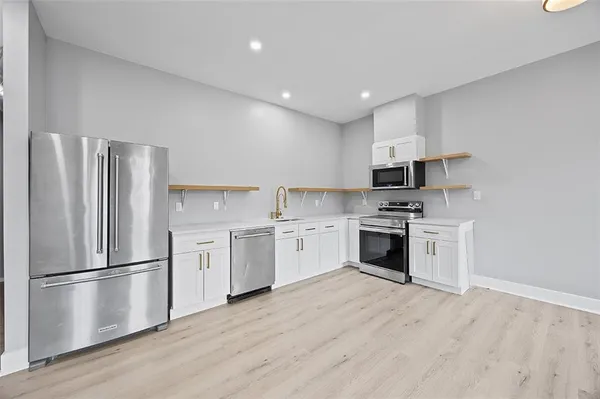 a kitchen with a refrigerator stove and wooden floors