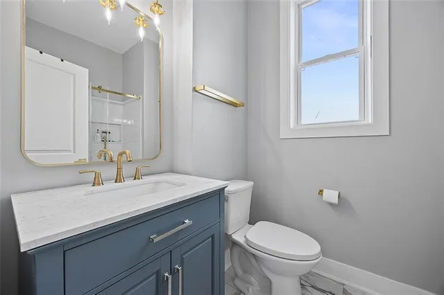 a bathroom with a granite countertop toilet sink and mirror