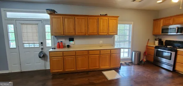 a kitchen with stainless steel appliances granite countertop wooden cabinets a refrigerator a stove a sink and dishwasher with wooden floor