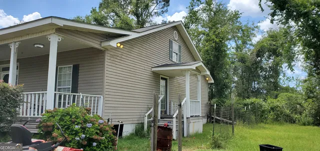 a view of a house with a small yard plants and large tree
