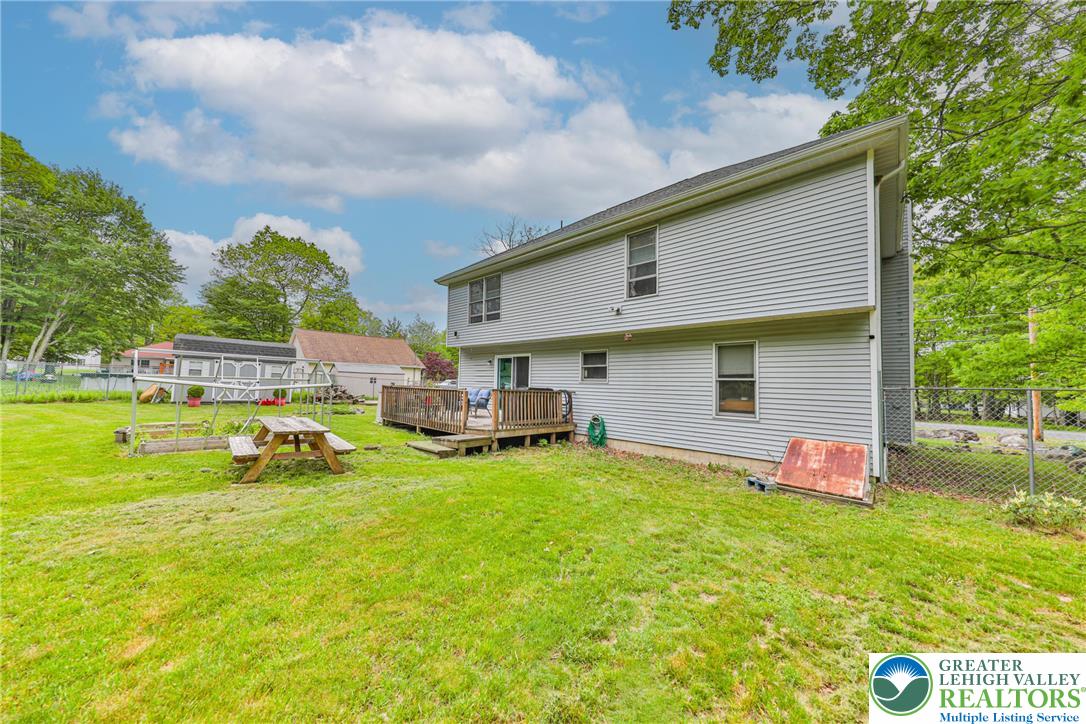 4608 Pine Ridge Drive West Bushkill, PA 18324 - Photo 52 of 62 A spacious yard with a wooden deck extends from the rear of the home, offering ample outdoor living space.