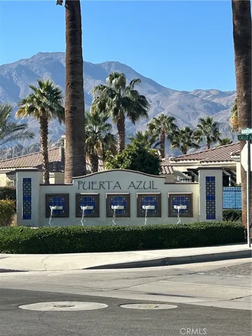 a view of a white house with a palm tree next to a road