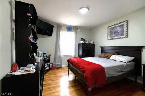 a bedroom with a bed and a flat tv screen on dresser