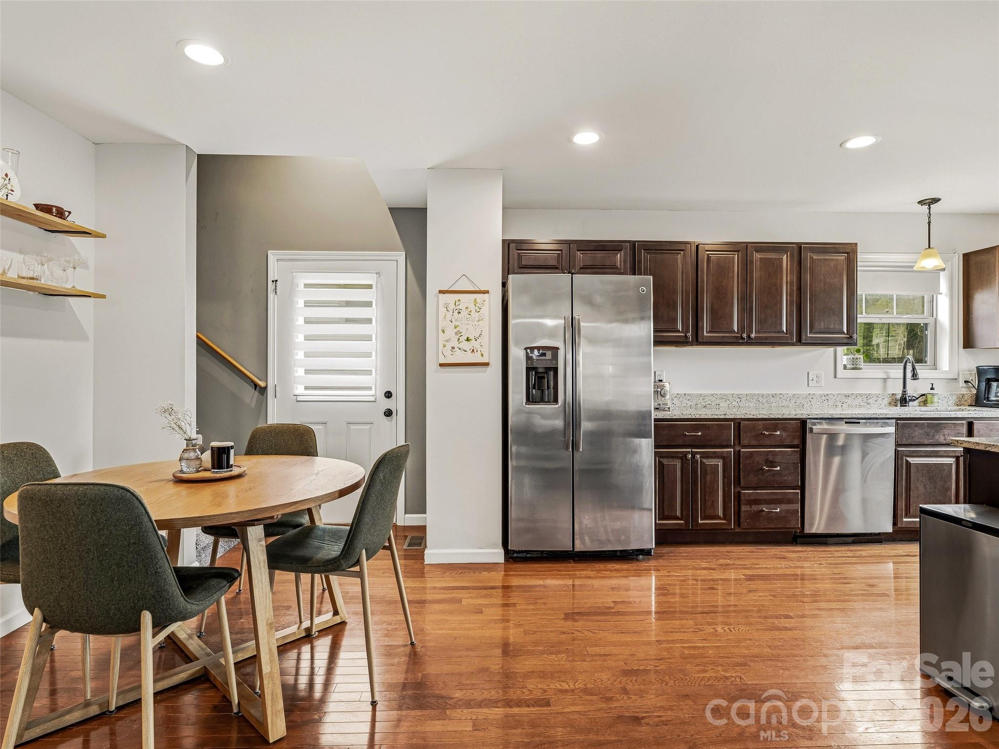 21 Yarrow Meadow Road Weaverville, NC 28787 - Photo 10 of 38 a kitchen with stainless steel appliances kitchen island granite countertop a refrigerator a stove a sink dishwasher with a dining table and chairs with wooden floor