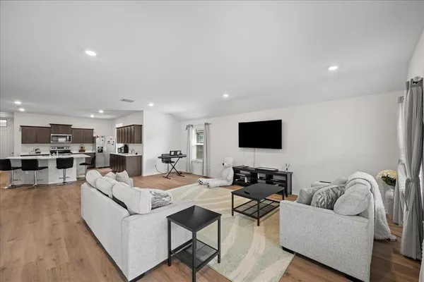 a living room with furniture kitchen view and a flat screen tv