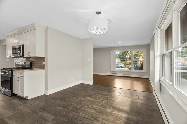 a view of an empty room with window and wooden floor