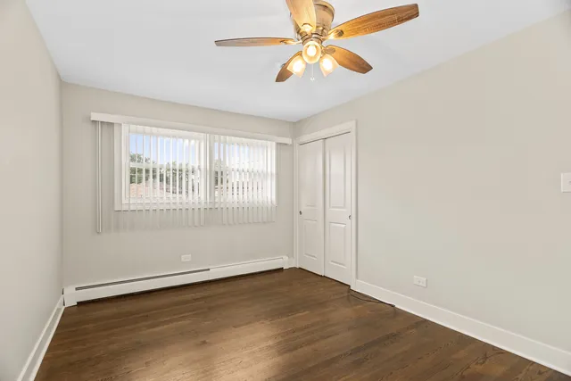 an empty room with wooden floor fan and windows