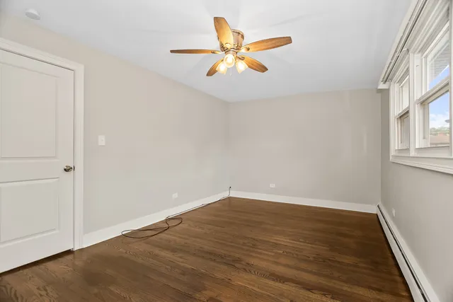 an empty room with wooden floor fan and windows