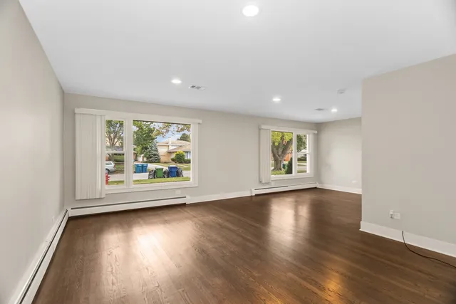 an empty room with wooden floor and window
