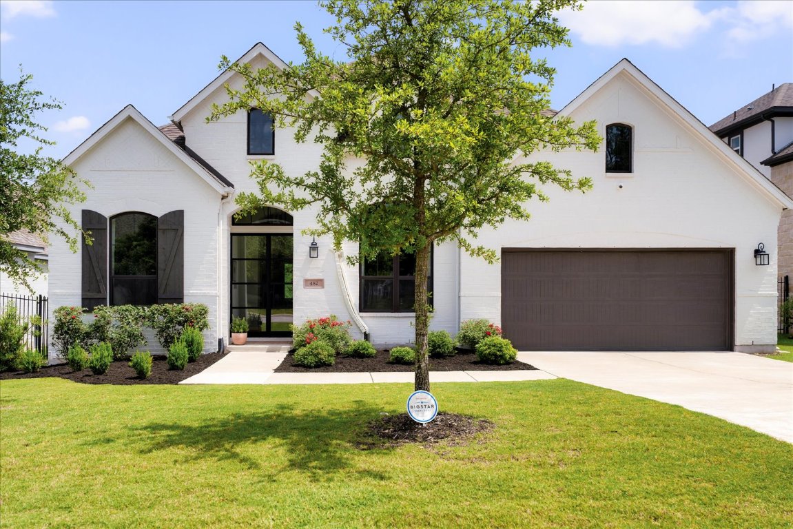 A picture-perfect entry: classic white exterior, flourishing rose bushes, and bold double black Carrera doors for a striking welcome.