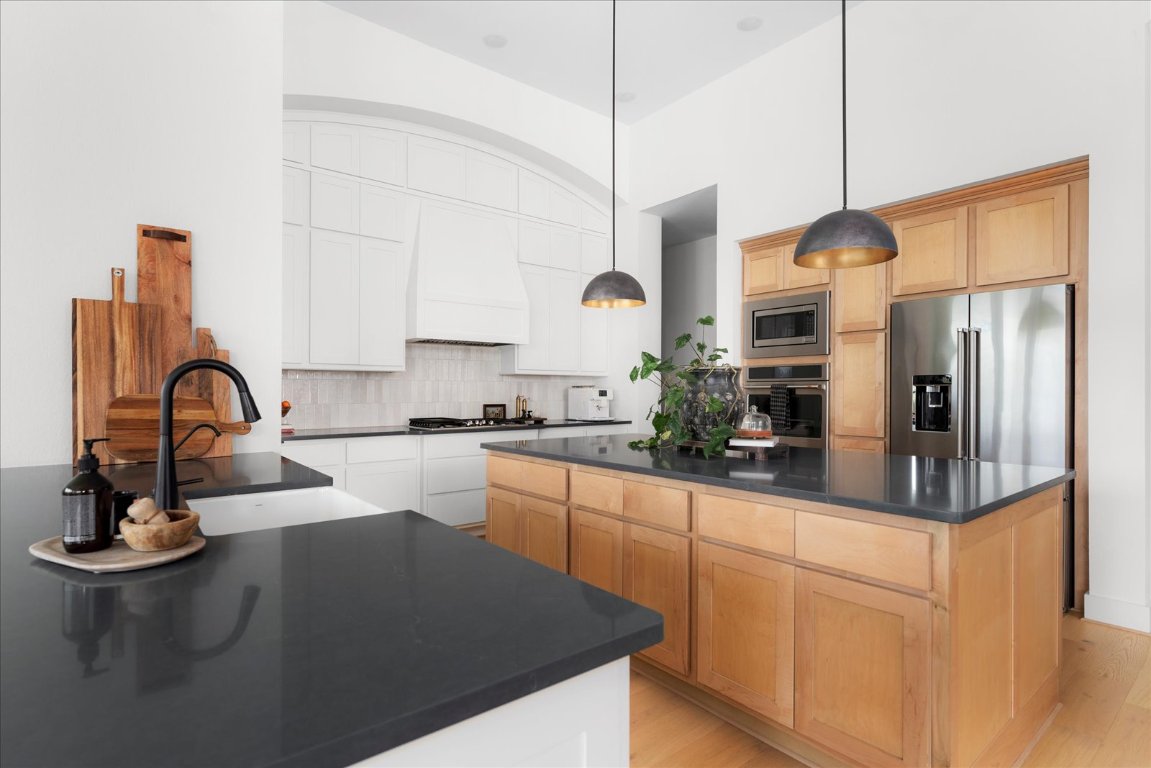 482 Running Bird Road Austin, TX 78737 - Photo 11 of 38 A chef’s dream kitchen with double islands, ceiling-height custom cabinetry, under-cabinet lighting, a farmhouse sink, double ovens, and designer pendant lights that complete the elevated look.