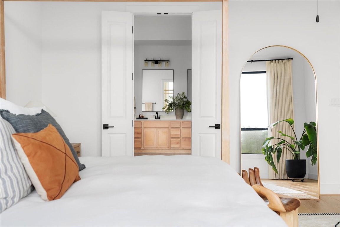 482 Running Bird Road Austin, TX 78737 - Photo 21 of 38 Wake up to nature’s beauty in this peaceful primary bedroom, complete with expansive windows and custom treatments for the perfect balance of light and privacy.