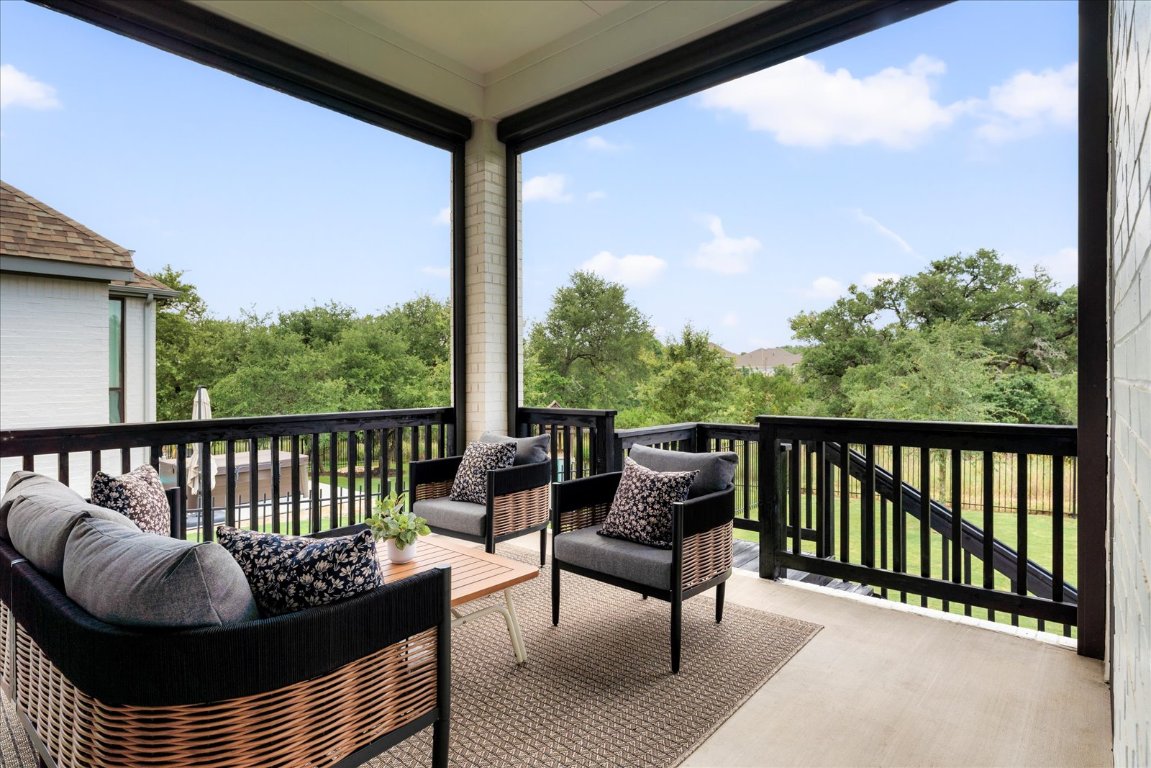 482 Running Bird Road Austin, TX 78737 - Photo 34 of 38 A clean, serene patio with electric shades, sleek black-stained rails, and calming greenbelt views perfect for morning coffee or evening relaxation.