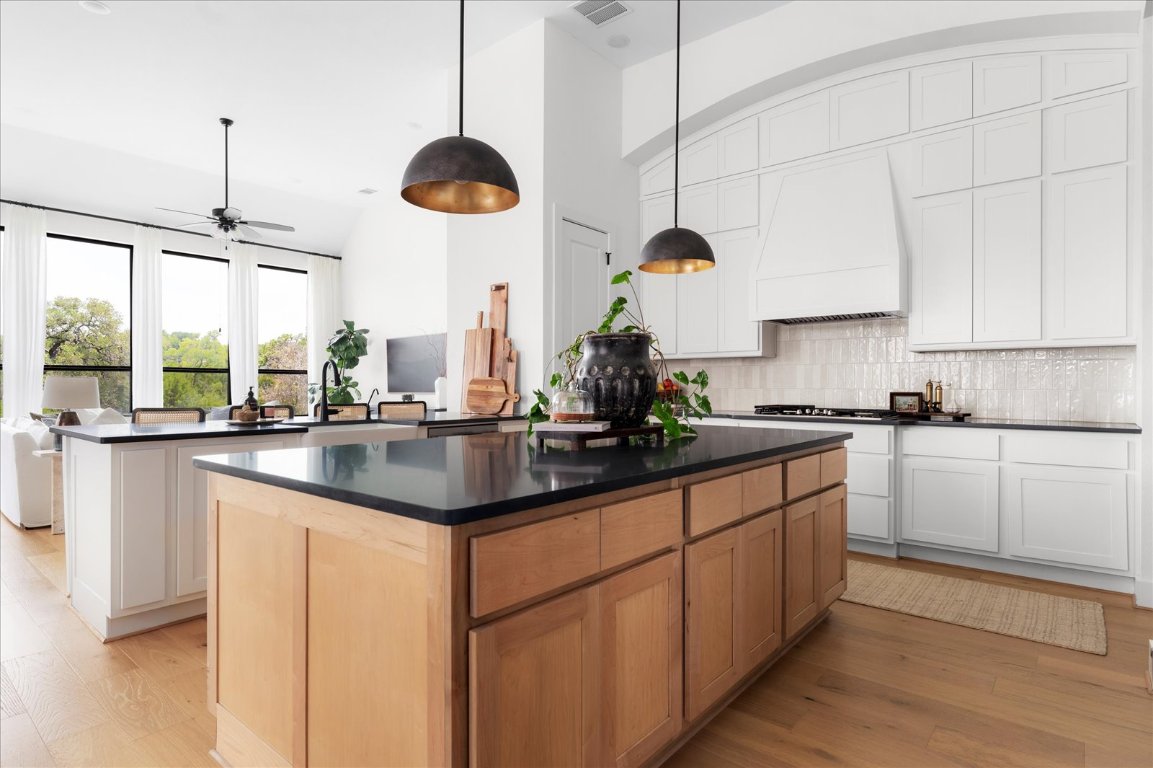 482 Running Bird Road Austin, TX 78737 - Photo 10 of 38 A chef’s dream kitchen with double islands, ceiling-height custom cabinetry, under-cabinet lighting, a farmhouse sink, double ovens, and designer pendant lights that complete the elevated look.