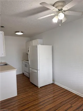 a view of a kitchen with a ceiling fan a refrigerator and a stove top oven
