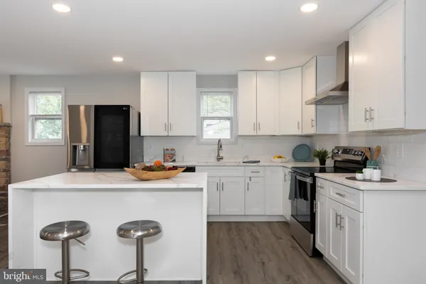 a kitchen with a sink a stove a refrigerator and white cabinets